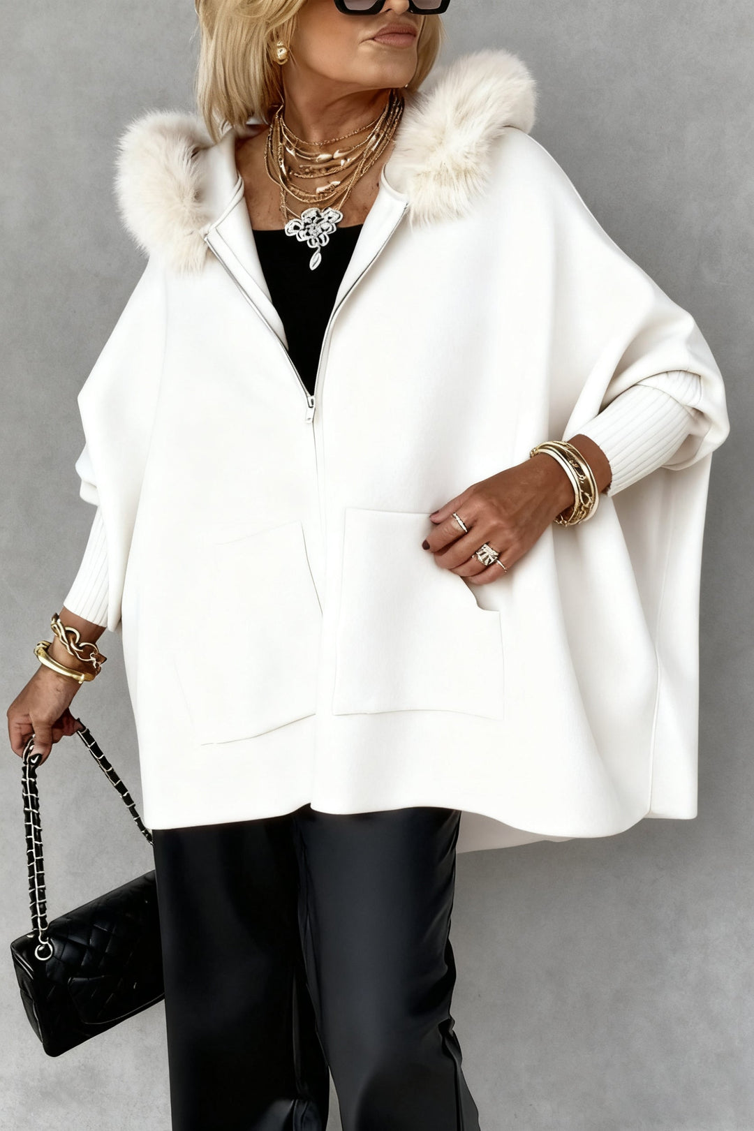 Mantella invernale calda per donna con cappuccio in pelliccia sintetica. Cappotto oversize, elegante e di moda.
