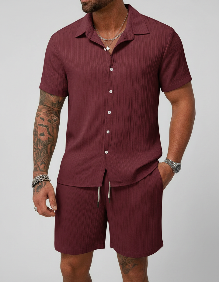 Uomo indossa completo estivo casual: camicia a maniche corte e pantaloncini coordinati per un look fresco.