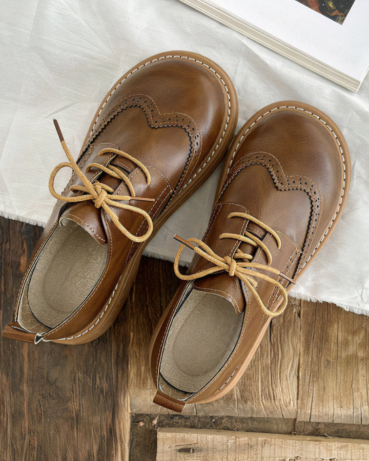 Donna che indossa scarpe Oxford piatte in pelle caffè, camminando con comfort e stile classico per ogni giorno.