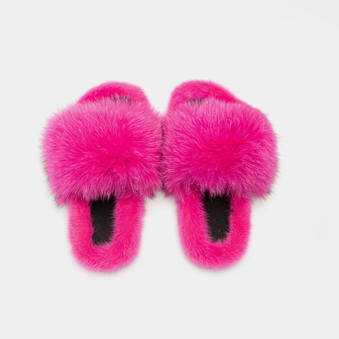 Primo piano di pantofole da donna fucsia, evidenziando la texture della pelliccia e la suola antiscivolo.