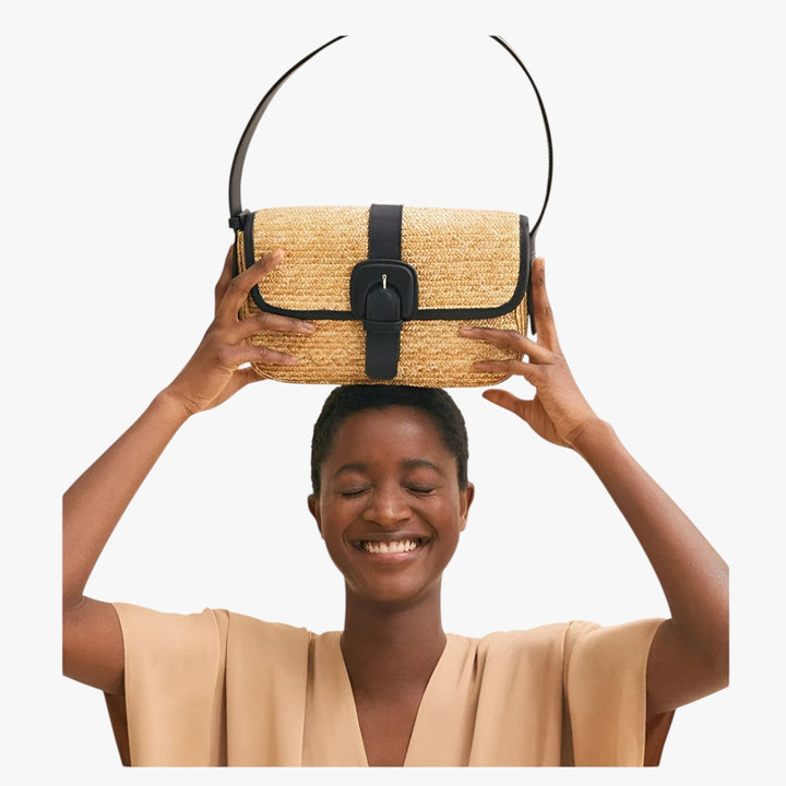 Donna con borsa a spalla marrone intrecciata, accessorio elegante e pratico per ogni occasione.