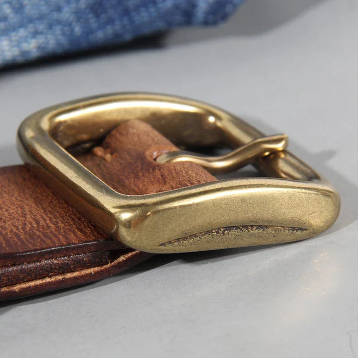 Primo piano: fibbia in ottone massiccio su cintura uomo artigianale in pelle. Accessorio iconico per jeans.