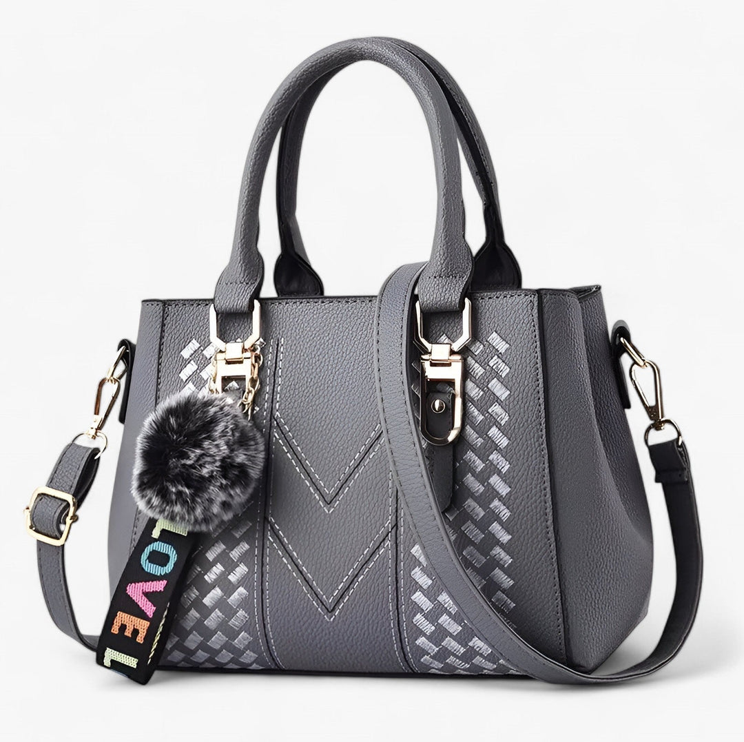 Borsa donna sofisticata con pompon e tracolla, finitura liscia ed elegante.