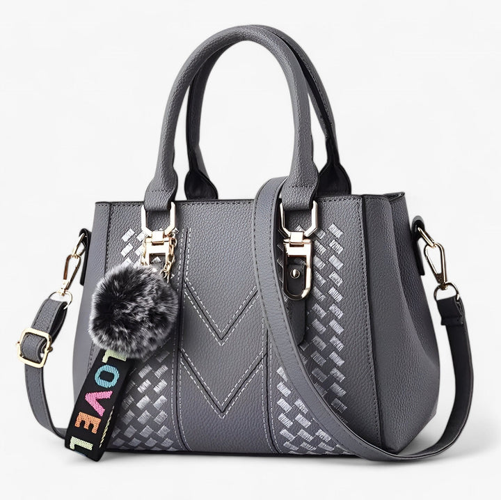 Borsa donna sofisticata con pompon e tracolla, finitura liscia ed elegante.