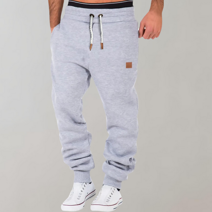 Pantaloni tuta uomo moderni, colore grigio mélange, vestibilità rilassata per massimo comfort sportivo e casual athleisure.
