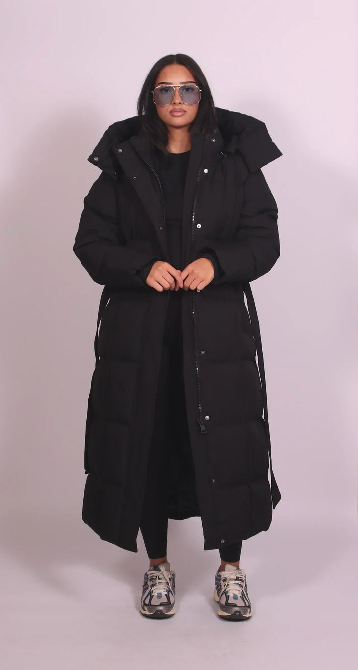 Caldo piumino donna lungo marrone per inverno, con cappuccio, cintura in vita e collo alto, stile elegante.