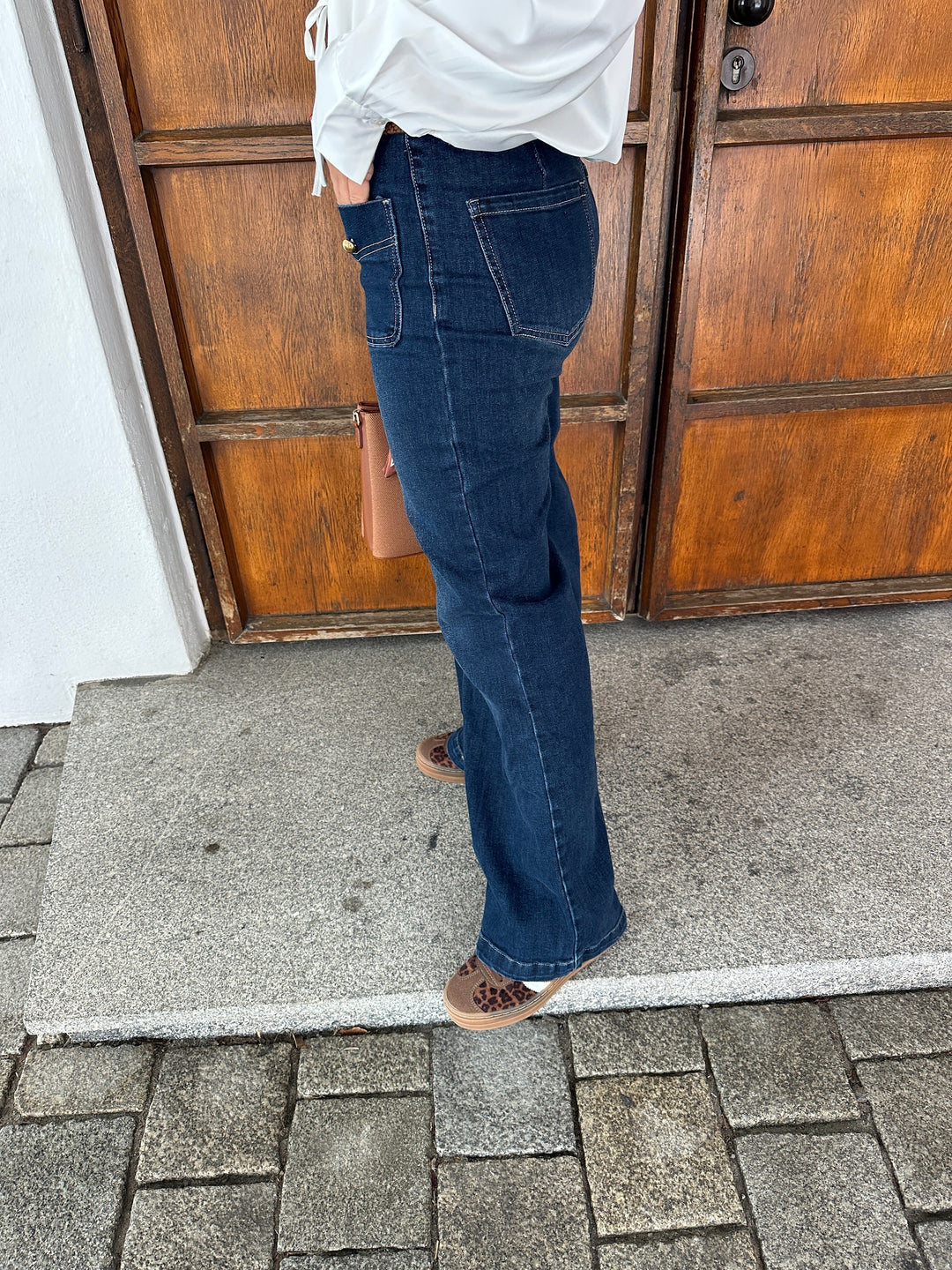 Dettaglio vita alta e bottoni dorati frontali dei jeans donna a gamba larga. Pantaloni eleganti per un look distintivo.