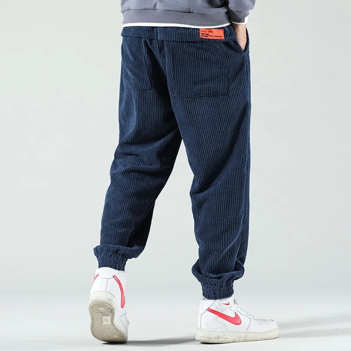 Pantaloni uomo a coste blu scuro, mostrano la texture del tessuto e la coulisse, perfetti per comfort e stile.