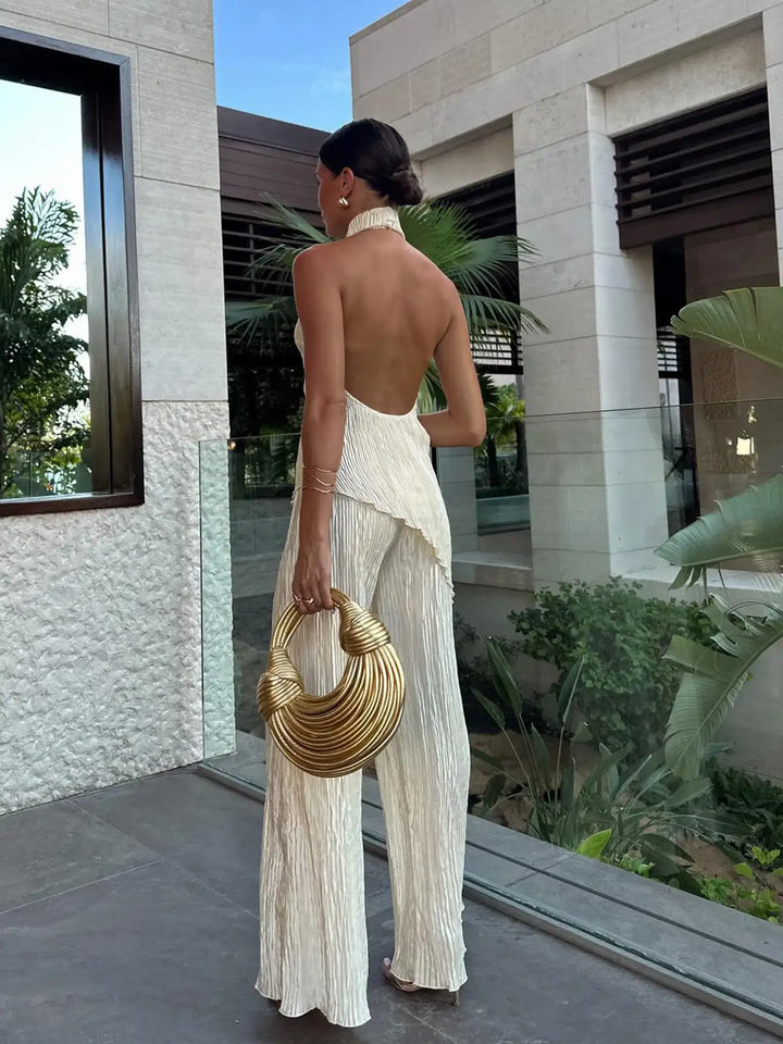Abito due pezzi plissettato donna, top scollo halter e pantaloni ampi. Outfit elegante moderno per ogni evento.