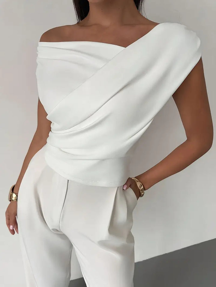 Donna che indossa top nero con spalle drappeggiate. Girocollo, maniche corte. Abbigliamento casual elegante.