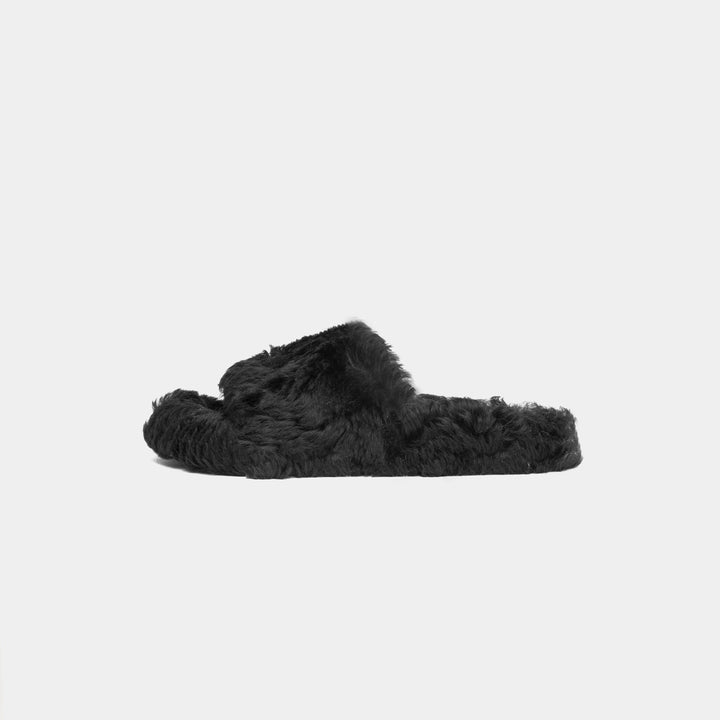 Comode pantofole da donna nere con dettagli in montone. Calzature morbide e accoglienti, ideali per l'inverno a casa.