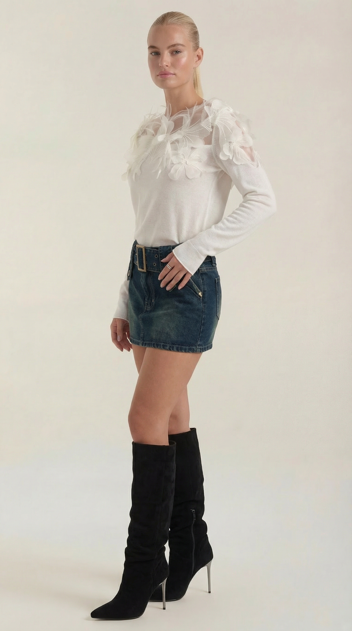 Primo piano di maglione donna girocollo con raffinate piume nere sul polsino, per un tocco di moda femminile.