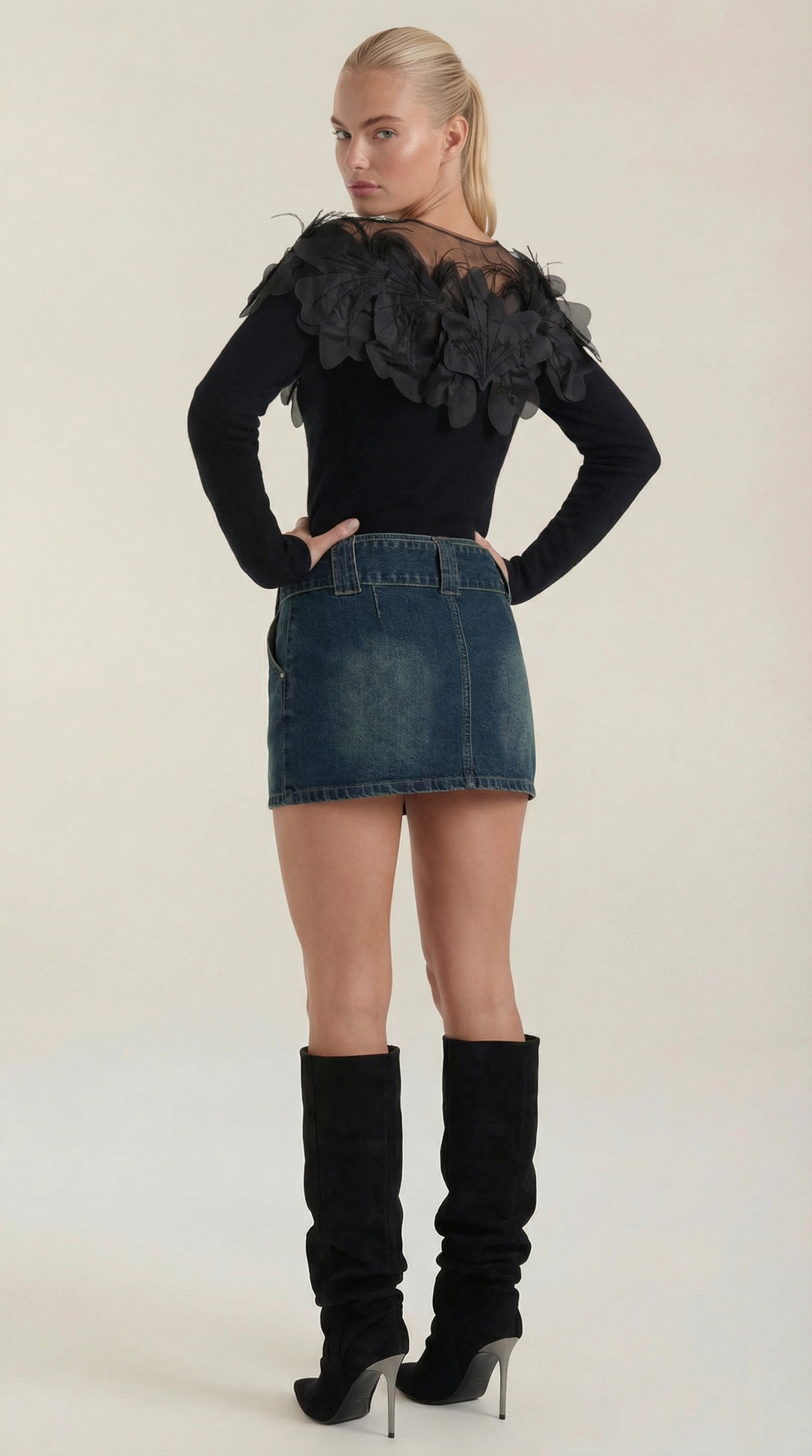 Maglione donna nero elegante con girocollo e piume posato su superficie, evidenziando il design per la moda.