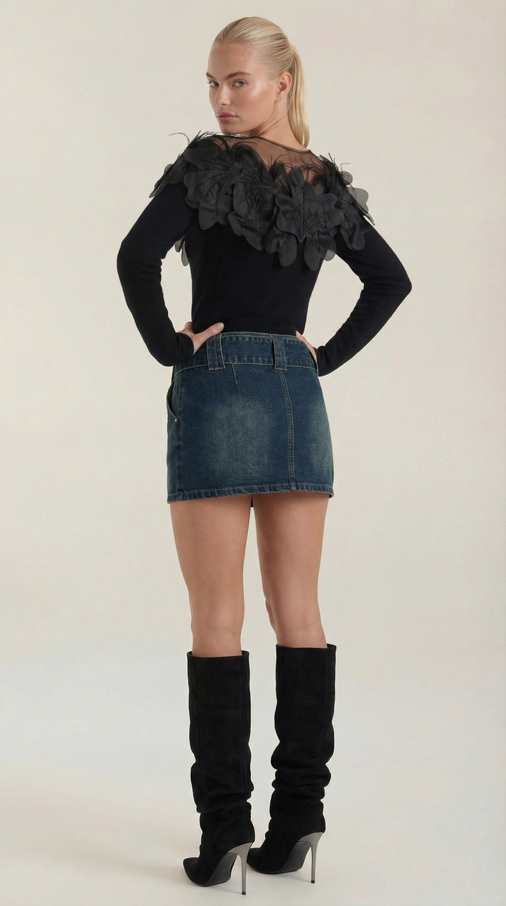 Maglione donna nero elegante con girocollo e piume posato su superficie, evidenziando il design per la moda.