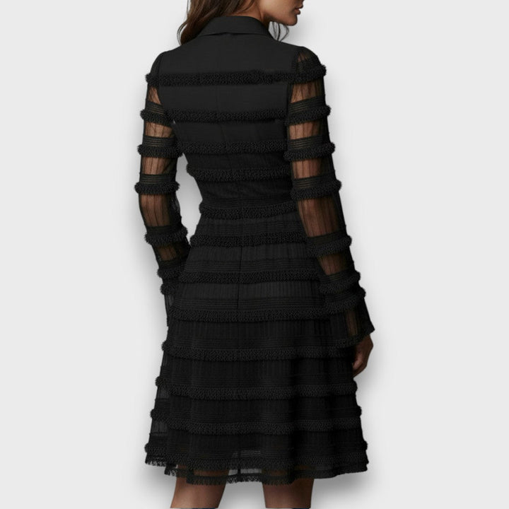 Modella indossa vestito donna nero svasato con scollo a V e maniche lunghe. Outfit moda femminile autunno inverno.