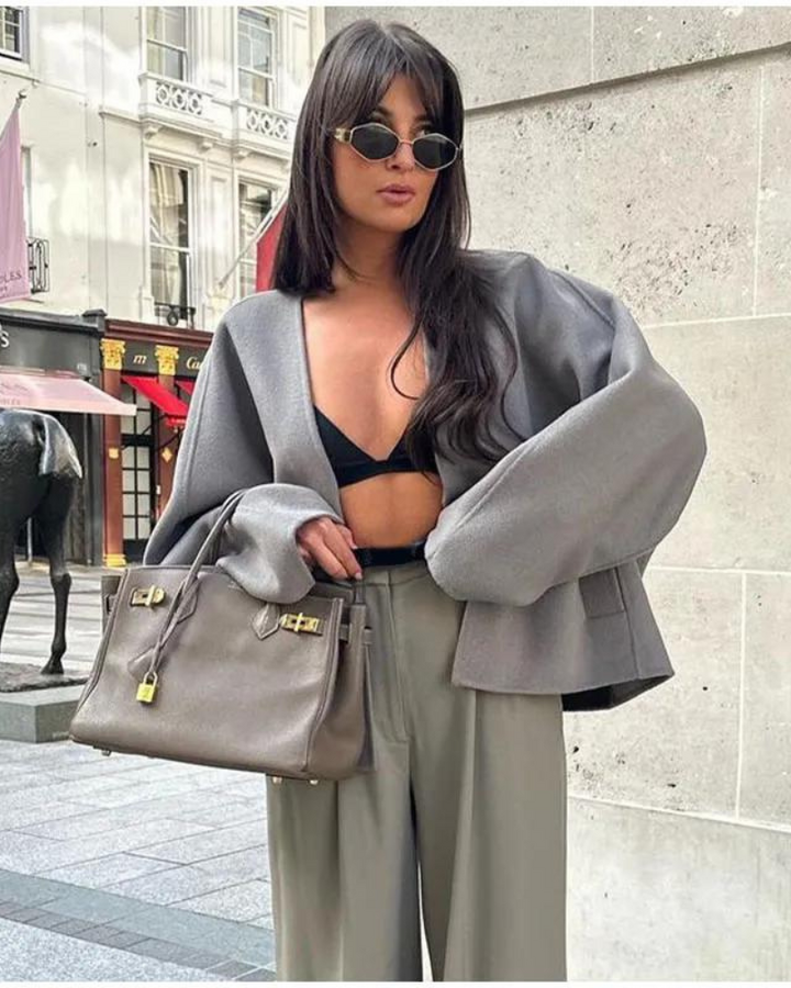 Moda donna: giacca corta grigia monopetto con scollo a V, abbinata a un outfit moderno.