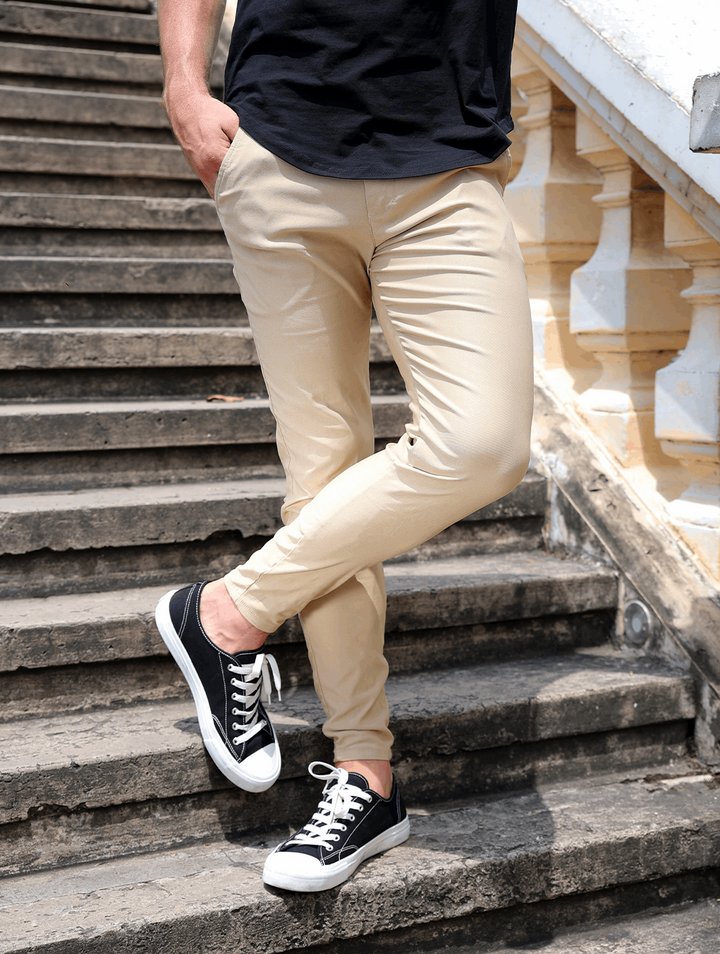 Pantaloni beige uomo slim fit, vita elasticizzata. Dettaglio tasche posteriori, stile e praticità.