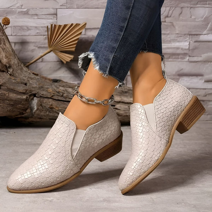 Dettaglio laterale di scarpe Oxford nere da donna. Tacco largo e finitura elegante per ogni occasione.