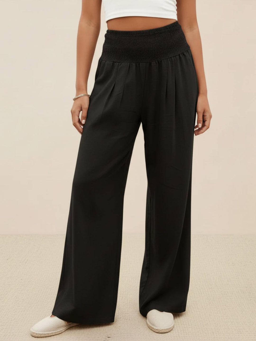 Donna indossa pantaloni a vita alta, gamba larga. Un look elegante e comodo, ideale per il giorno o la sera.