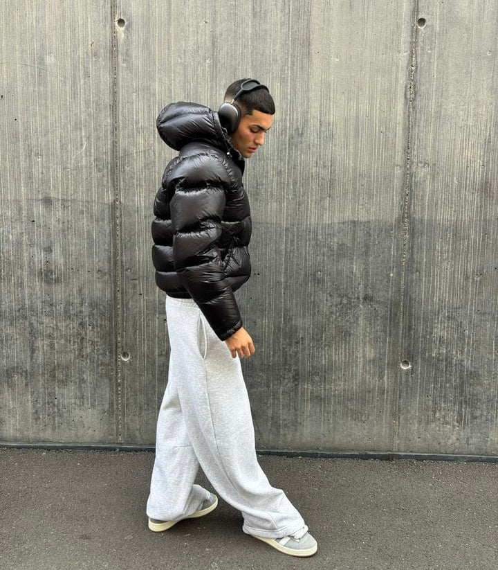 Giacca invernale uomo nera lucida con cappuccio, piumino casual elegante per affrontare il freddo urbano.