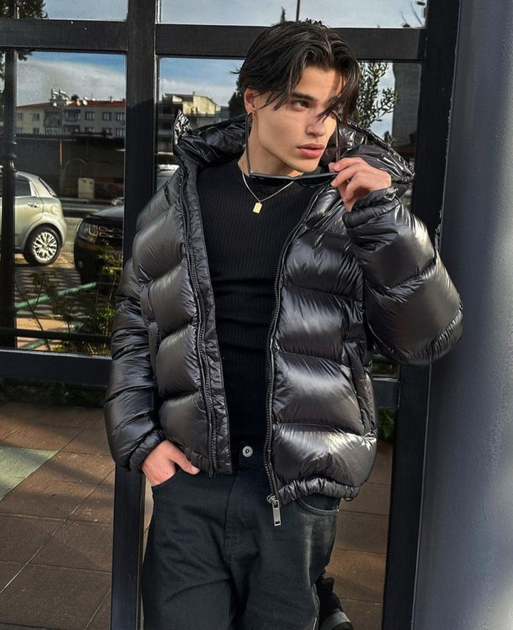 Piumino uomo lucido nero, giacca invernale con cappuccio. Stile urbano e calore per un look moderno.