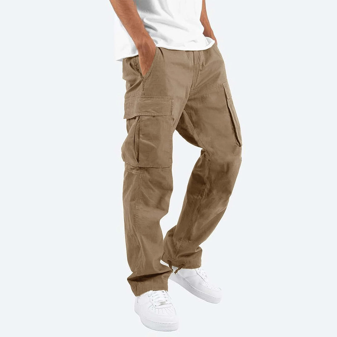 Uomo in piedi con pantaloni cargo, esaltando la silhouette casual e le tasche pronte all'uso per l'autunno.