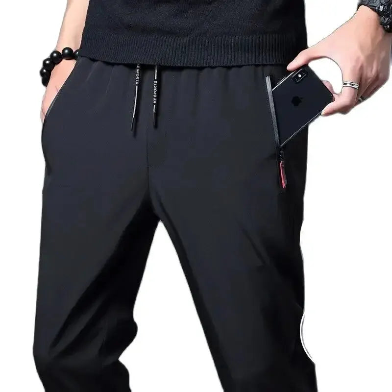 Vista ravvicinata di pantaloni uomo slim fit neri con vita elastica e tasche zip, perfetti per il viaggio.