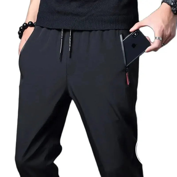 Vista ravvicinata di pantaloni uomo slim fit neri con vita elastica e tasche zip, perfetti per il viaggio.