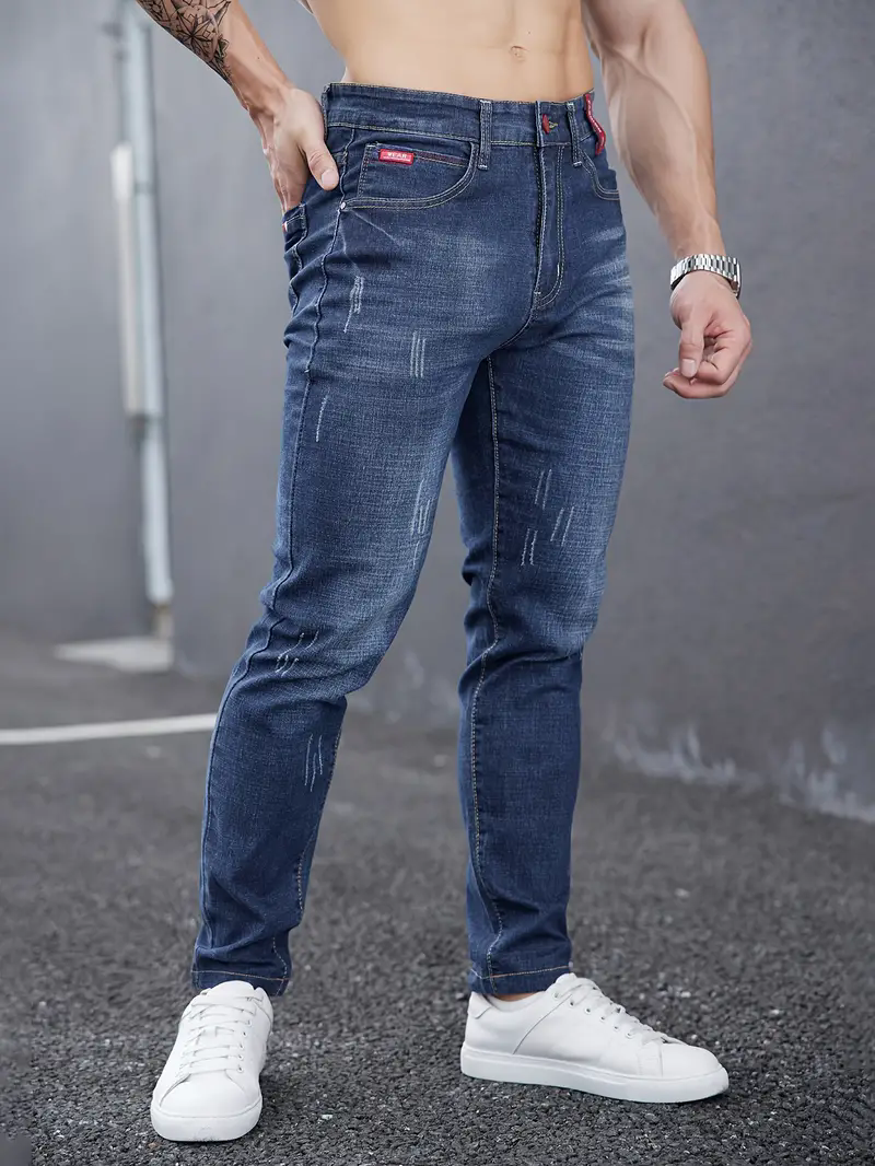 Jeans uomo tapered, denim blu scuro, vita media, chiusura bottoni. Vestibilità affusolata per ogni stile.