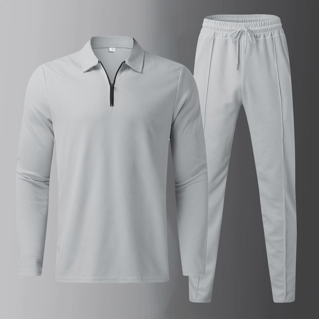 Set uomo grigio con polo a maniche lunghe e pantaloni jogger, perfetto per abbigliamento sportivo casual.