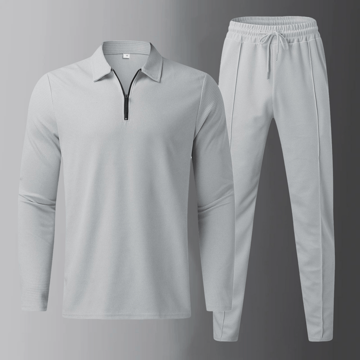 Set uomo grigio con polo a maniche lunghe e pantaloni jogger, perfetto per abbigliamento sportivo casual.