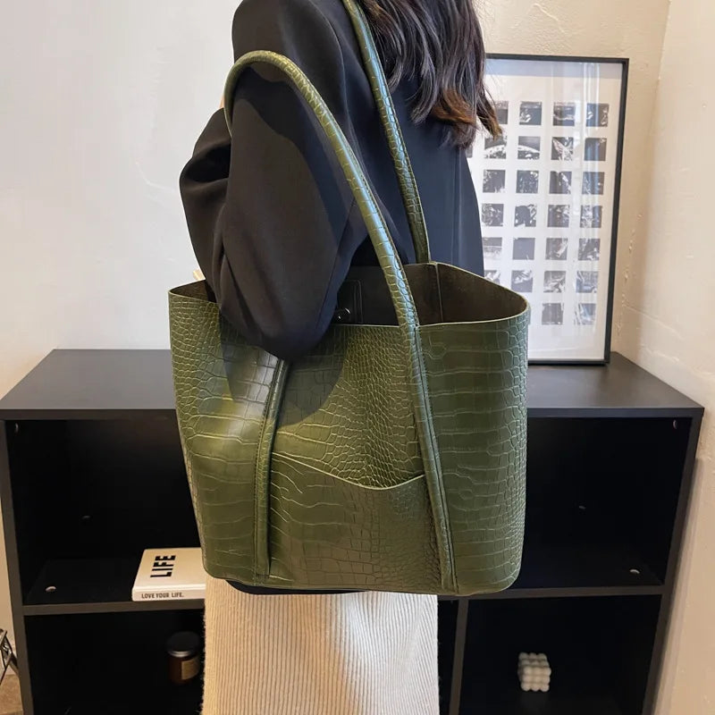 Dettaglio chiusura metallica dorata su borsa tracolla donna, pelle coccodrillo goffrata, tocco di lusso.