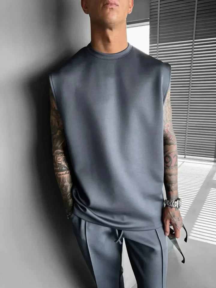 Stile moderno uomo: completo lounge con top senza maniche e pantaloni sartoriali, perfetto per il relax.