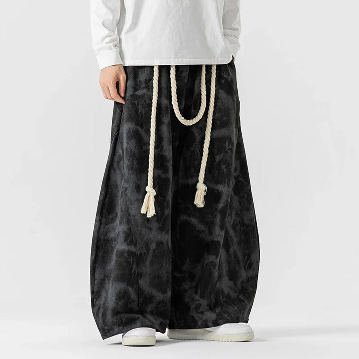 Pantaloni uomo casual tie-dye viola, bianco e nero, gamba larga con cordoncino, per un look comodo e di tendenza.