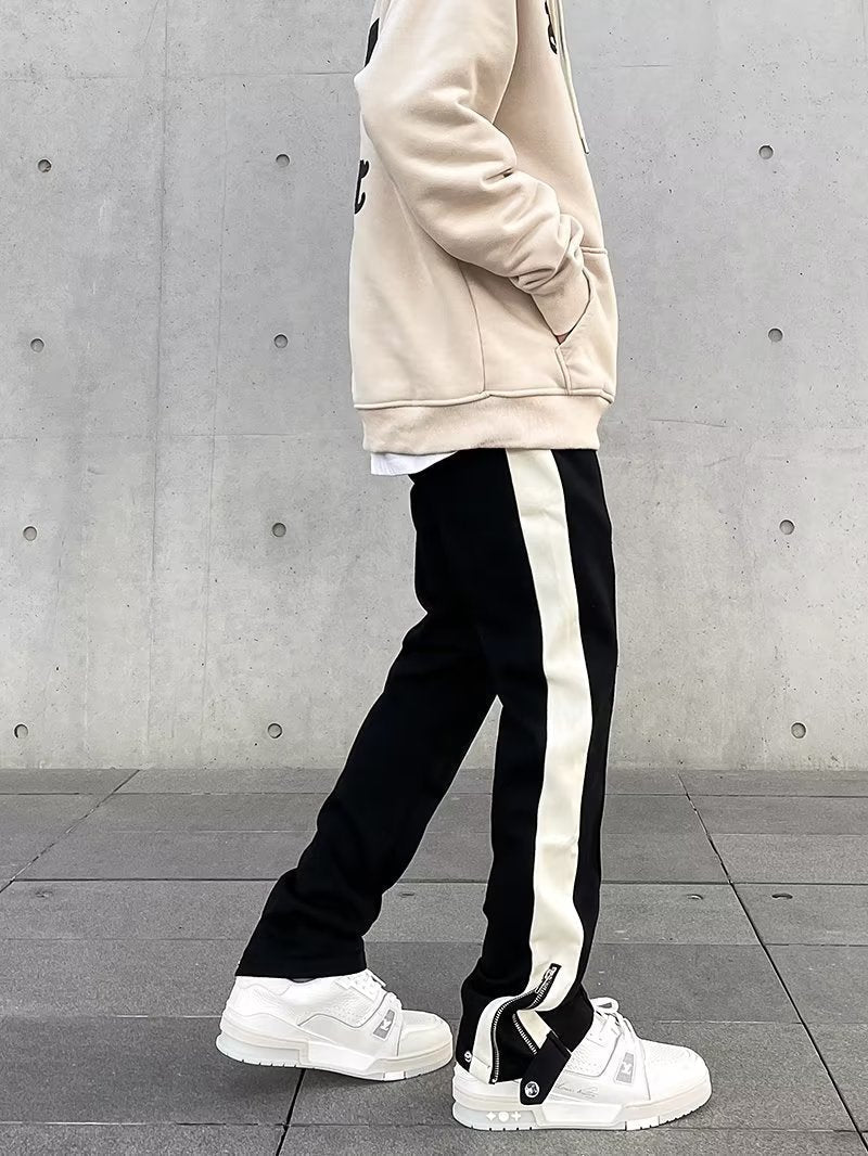 Uomo indossa pantaloni dritti streetwear neri con banda laterale, perfetti per un look casual urbano.