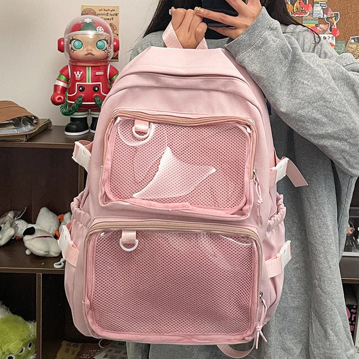 Zaino scuola ragazza Ita Bag rosa con tasche trasparenti, ideale per esporre accessori kawaii e badge.