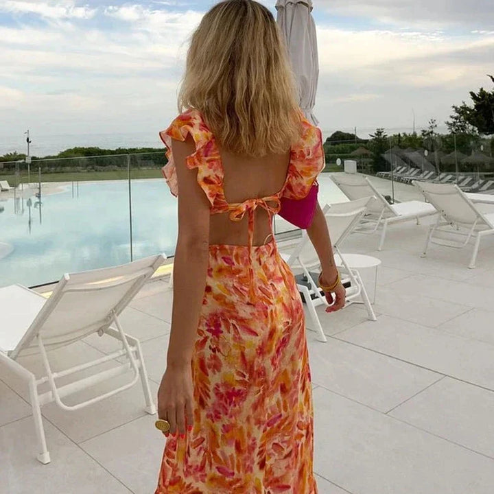 Abito lungo donna aderente arancione con schiena scoperta e volant, ideale per feste estive. Look elegante e sensuale.