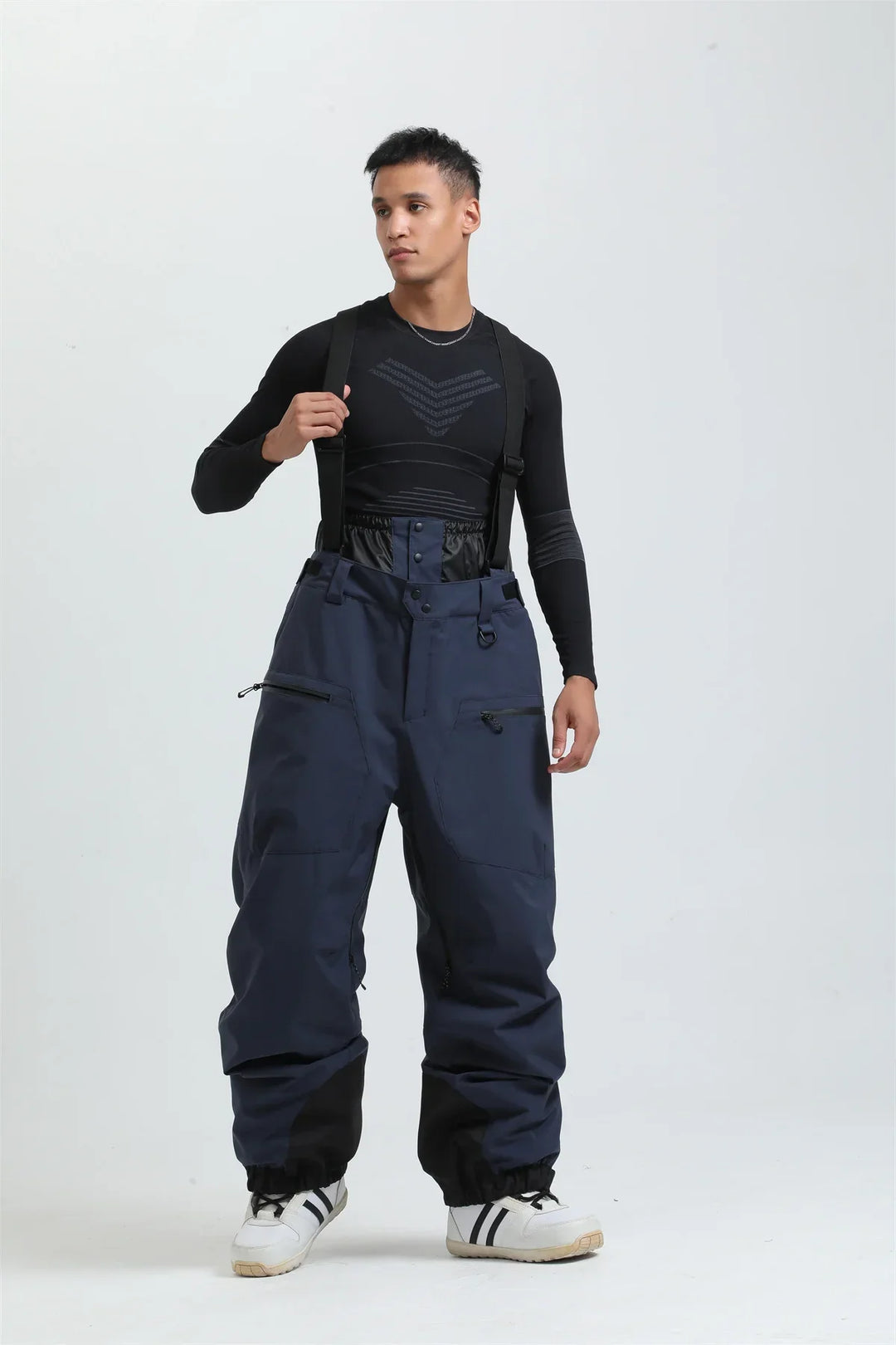 Dettaglio dei pantaloni da sci unisex neri, con bretelle regolabili e tessuto impermeabile per neve.