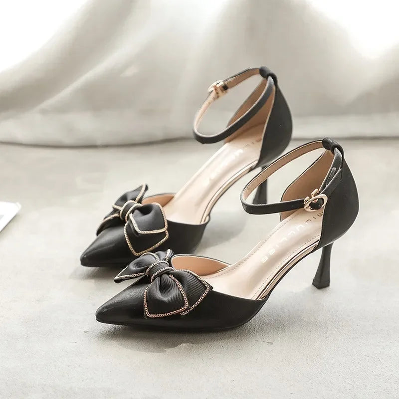 Scarpe formali décolleté donna con tacco medio, punta affusolata, fiocco satinato e cinturino alla caviglia.