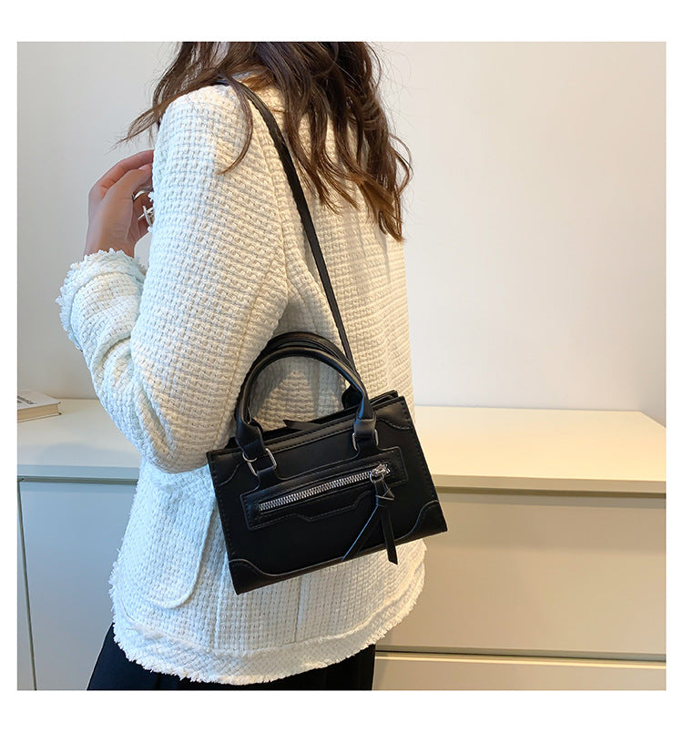 Compatta borsa a tracolla da donna in pelle nera, accessorio essenziale e di moda per un look versatile.