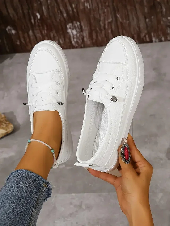 Comode scarpe basse da donna bianche con punta tonda e lacci, ideali per passeggiate e uso quotidiano in città.