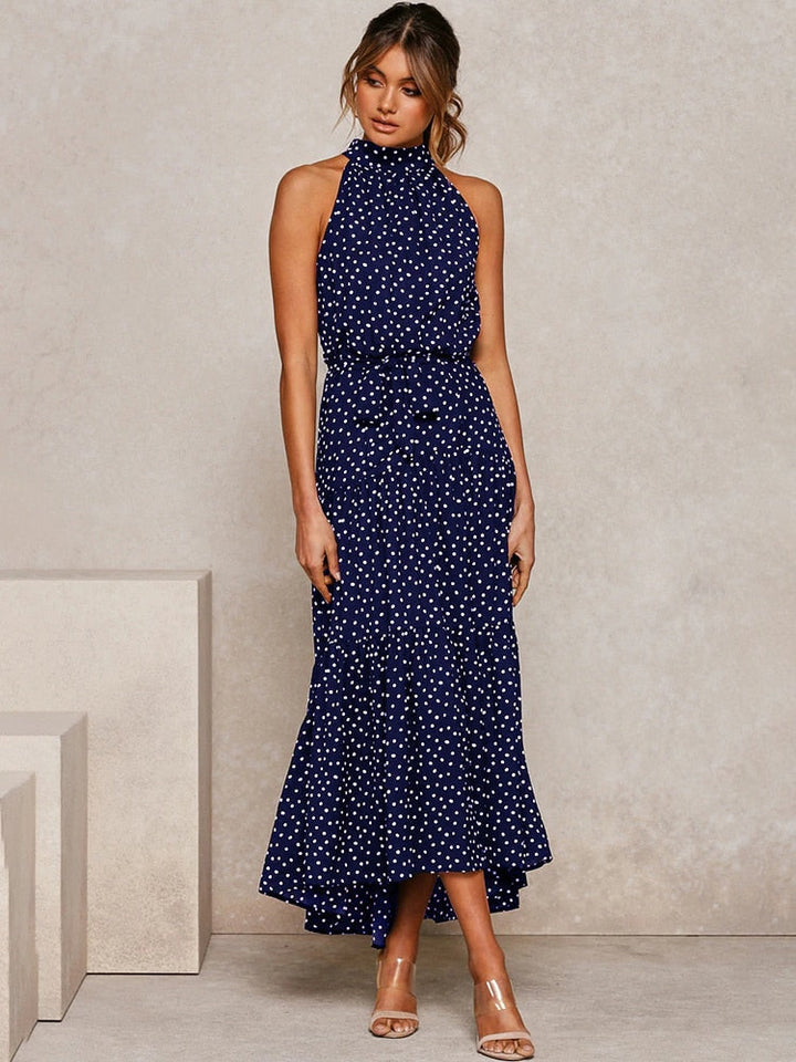 Abito midi nero a pois bianchi, modello svasato con scollo all'americana. Eleganza estiva per la donna.