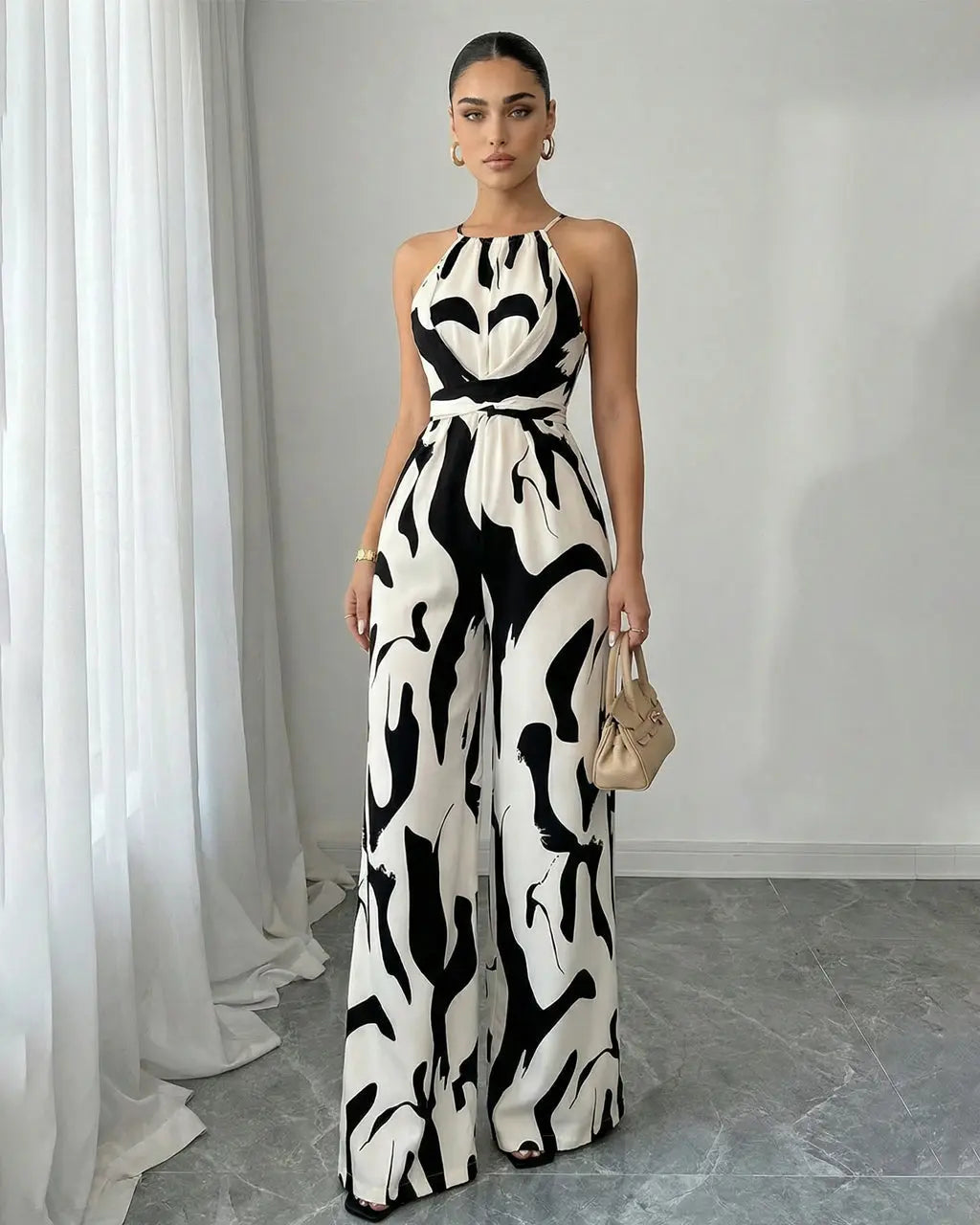 Tuta donna elegante chic con stampa astratta e scollo halter. Perfetta per la sera.