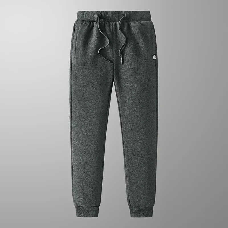 Uomo indossa pantaloni jogger invernali grigi, perfetti per attività sportiva o relax. Gamba affusolata alla moda.