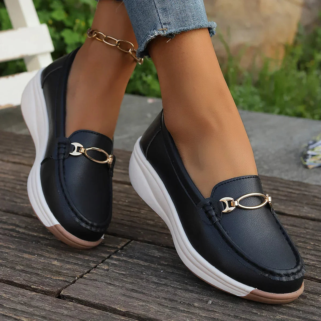 Mocassini donna slip-on neri con plateau e dettaglio dorato. Eleganti e confortevoli, perfetti per l'ufficio.