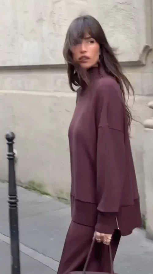 Donna indossa completo casa elegante. Set felpa collo alto e pantaloni larghi per un comfort sofisticato.
