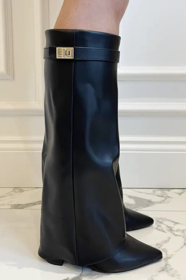 Donna indossa stivali alti in scamosciato con zeppa invisibile e fibbia dorata, look sofisticato e di tendenza.