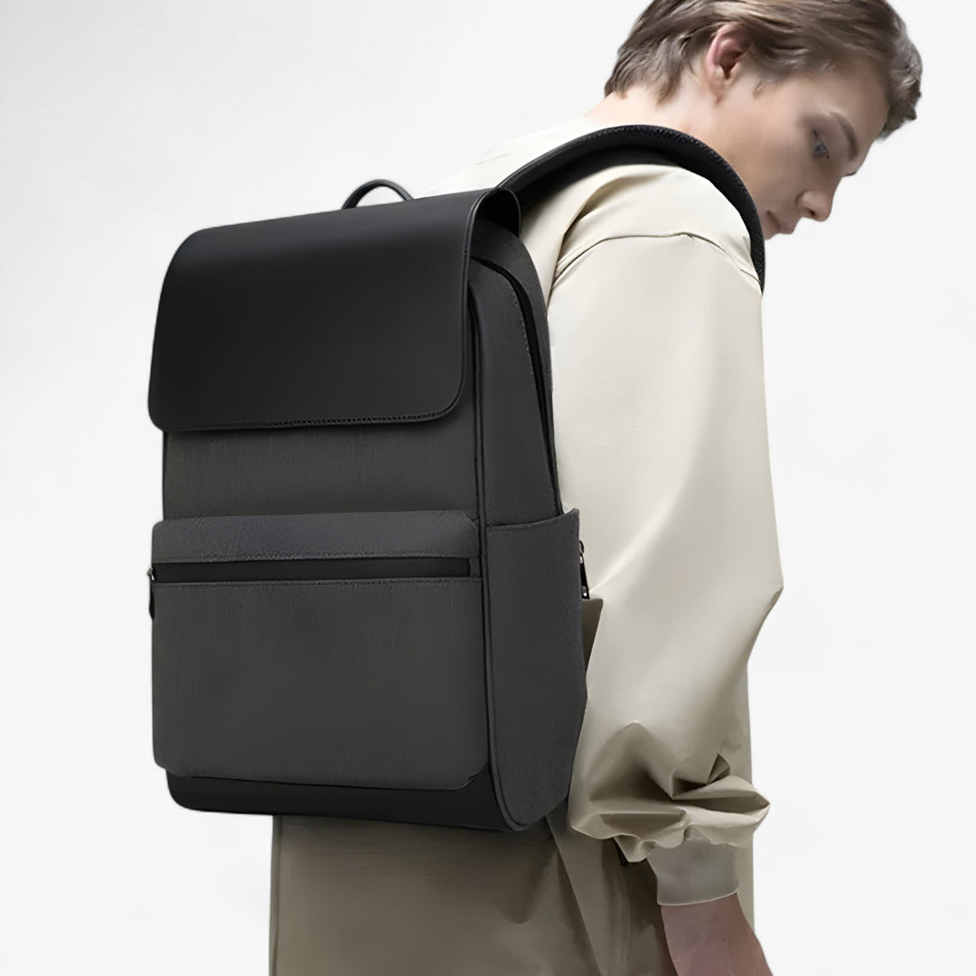 Uomo indossa zaino nero minimalista in ambiente urbano. Un accessorio pratico e stiloso per ogni giorno.
