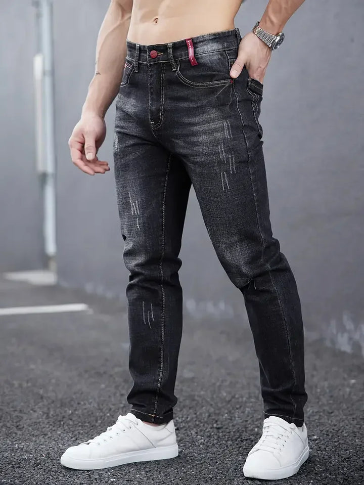 Dettaglio chiusura bottoni su jeans uomo tapered blu, vita media. Pantaloni denim casual affusolati.