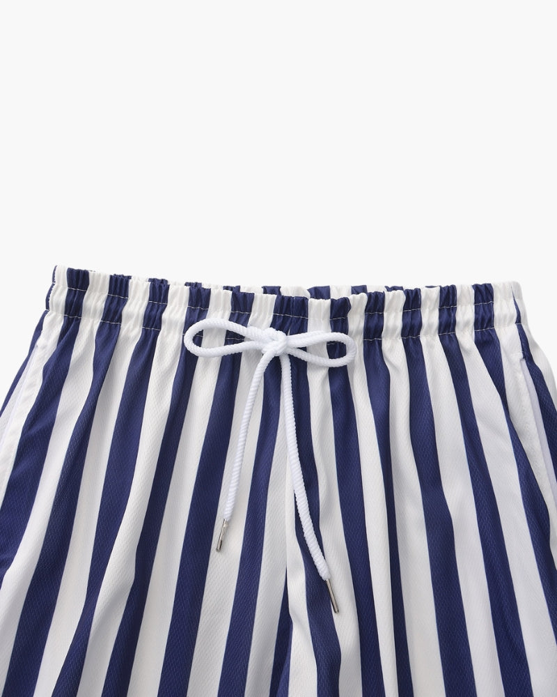 Uomo che indossa pantaloncini da bagno a righe, ideali per nuoto, spiaggia e sport acquatici. Asciugatura rapida.